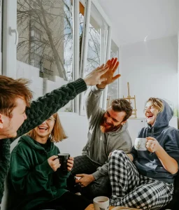Friends laughing and high-fiving in a living room