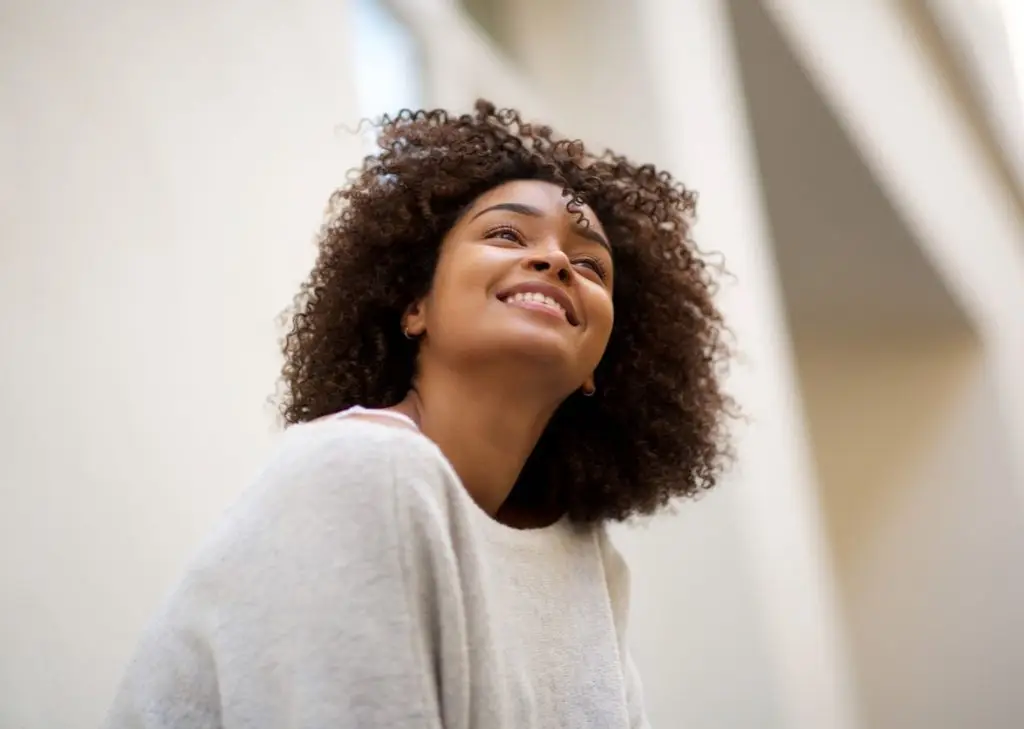 Close up portrait of happy african american woman with curly hair smiling outside