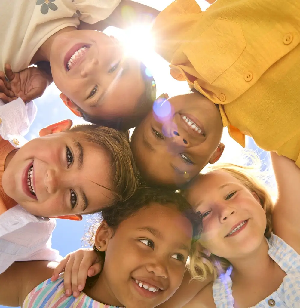 Group Of Multi-Cultural Children Friends Linking Arms Looking Down Into Camera