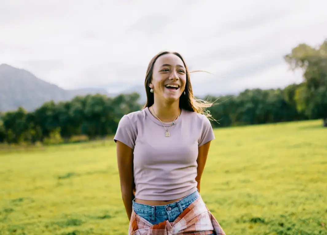 A smiling teenage girl, enjoying the beauty of Hawaii as a young adult. Joyful and content on a beautiful day in rural Kauai.