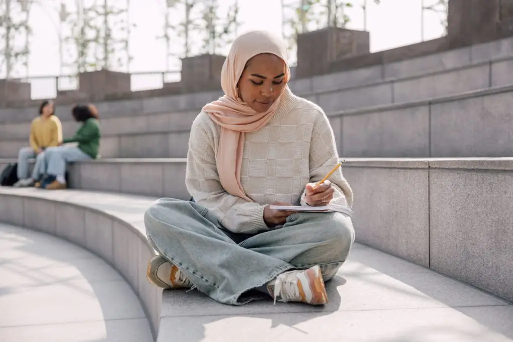 Teenage student reading and study using a mobile phone outdoors at public park.