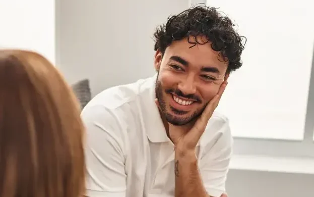 A woman with a clipboard taking notes while sitting on a couch with a smiling man.