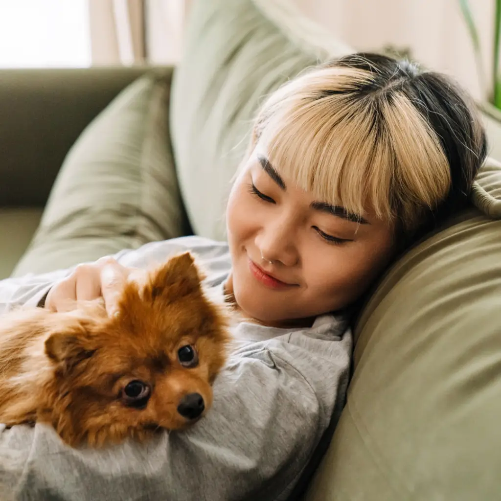 Girl sitting on a couch and smiling at her dog