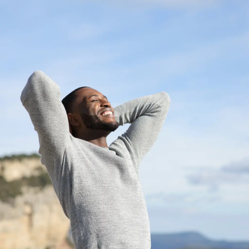 Man on a beach with his arms up looking relieved