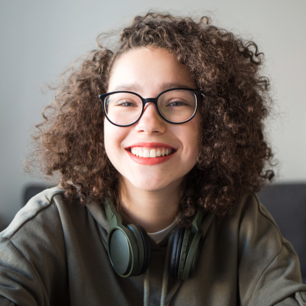 Smiling teen with curly hair wearing headphones around her neck