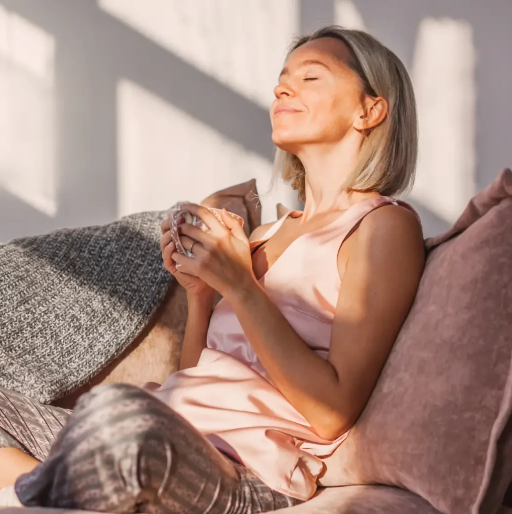 Woman on couch with a peaceful expression holding a coffee mug