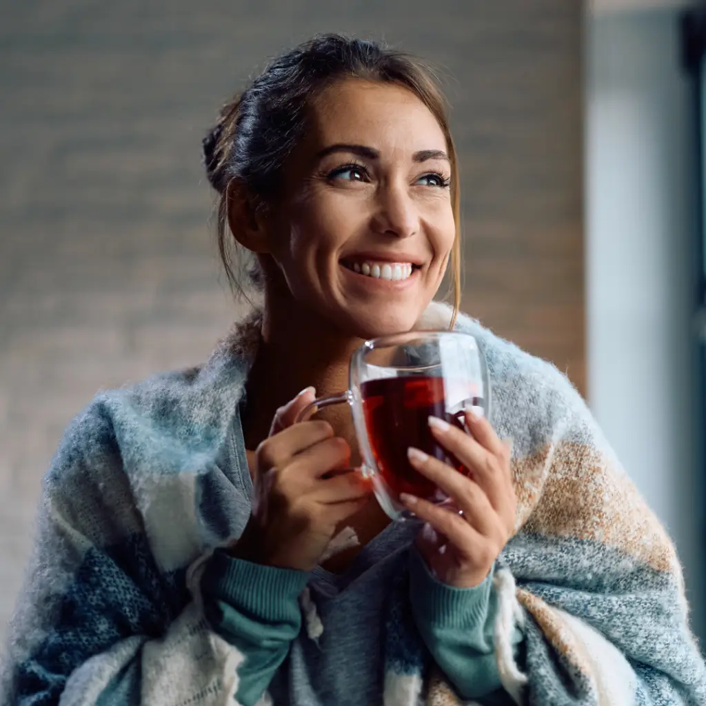 Woman smiling while holding tea in a glass mug