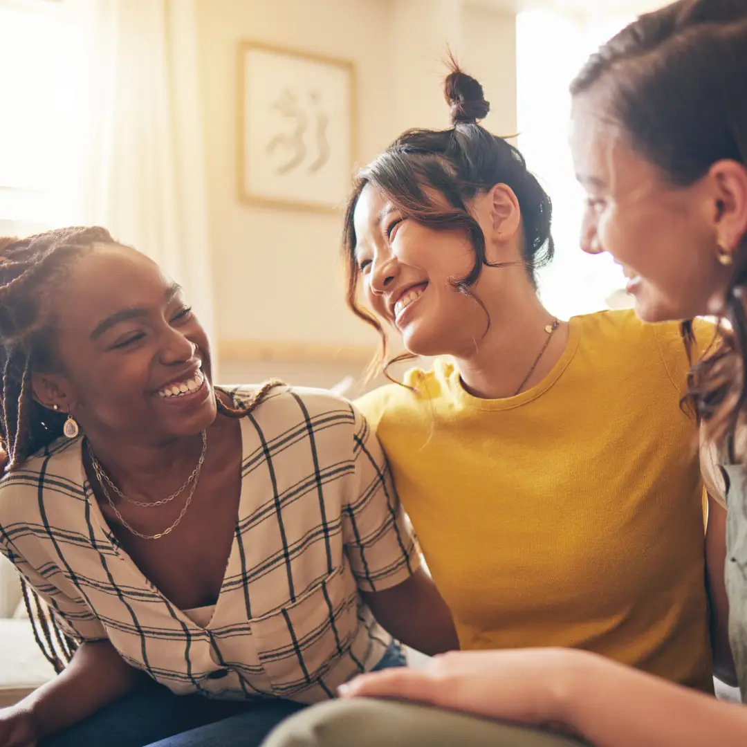 Young women laughing and smiling on a couch.