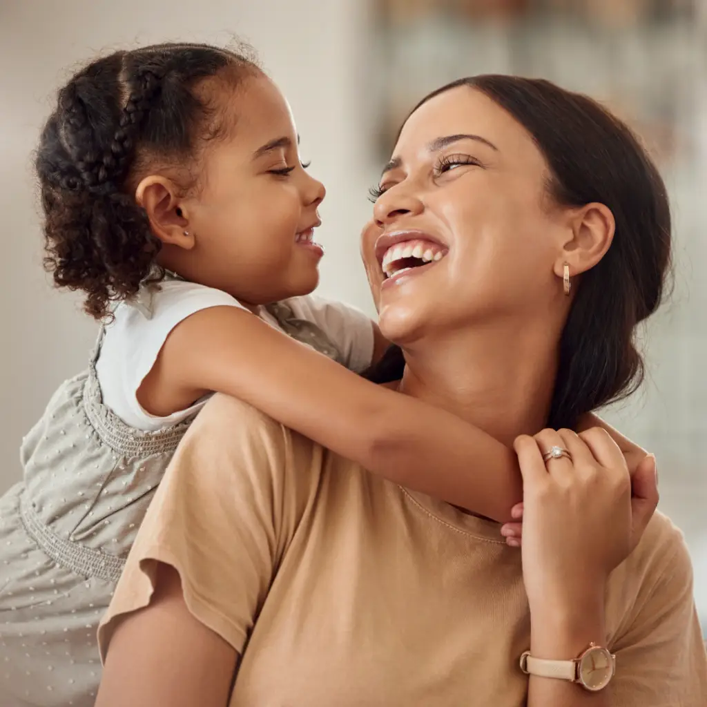 Happy daughter hugging her smiling mother and laughing.