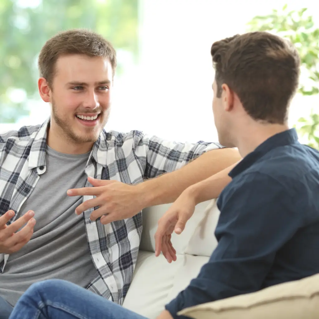 Two men sitting on a couch and chatting.
