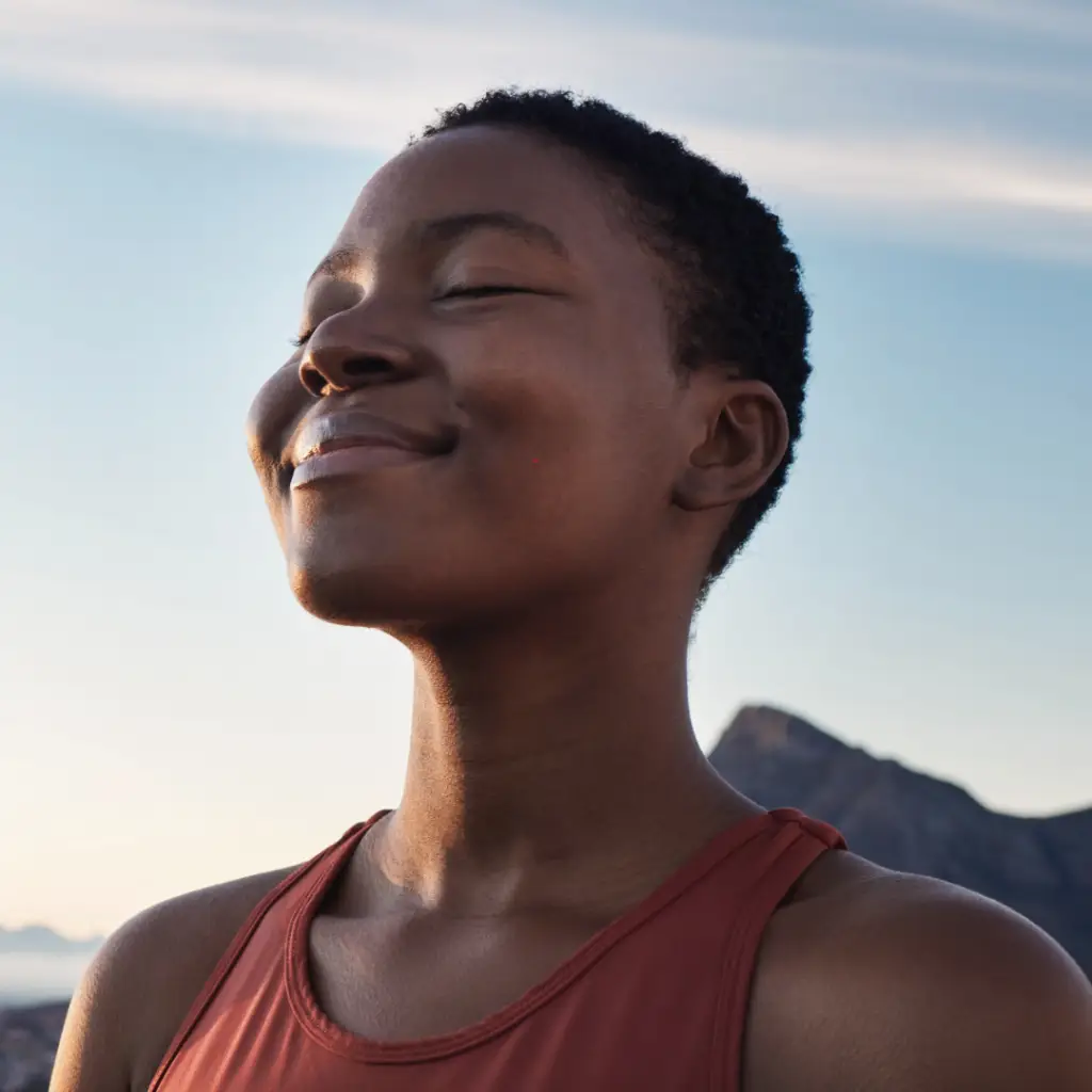 A woman being mindful and smiling thoughtfully with her eyes closed
