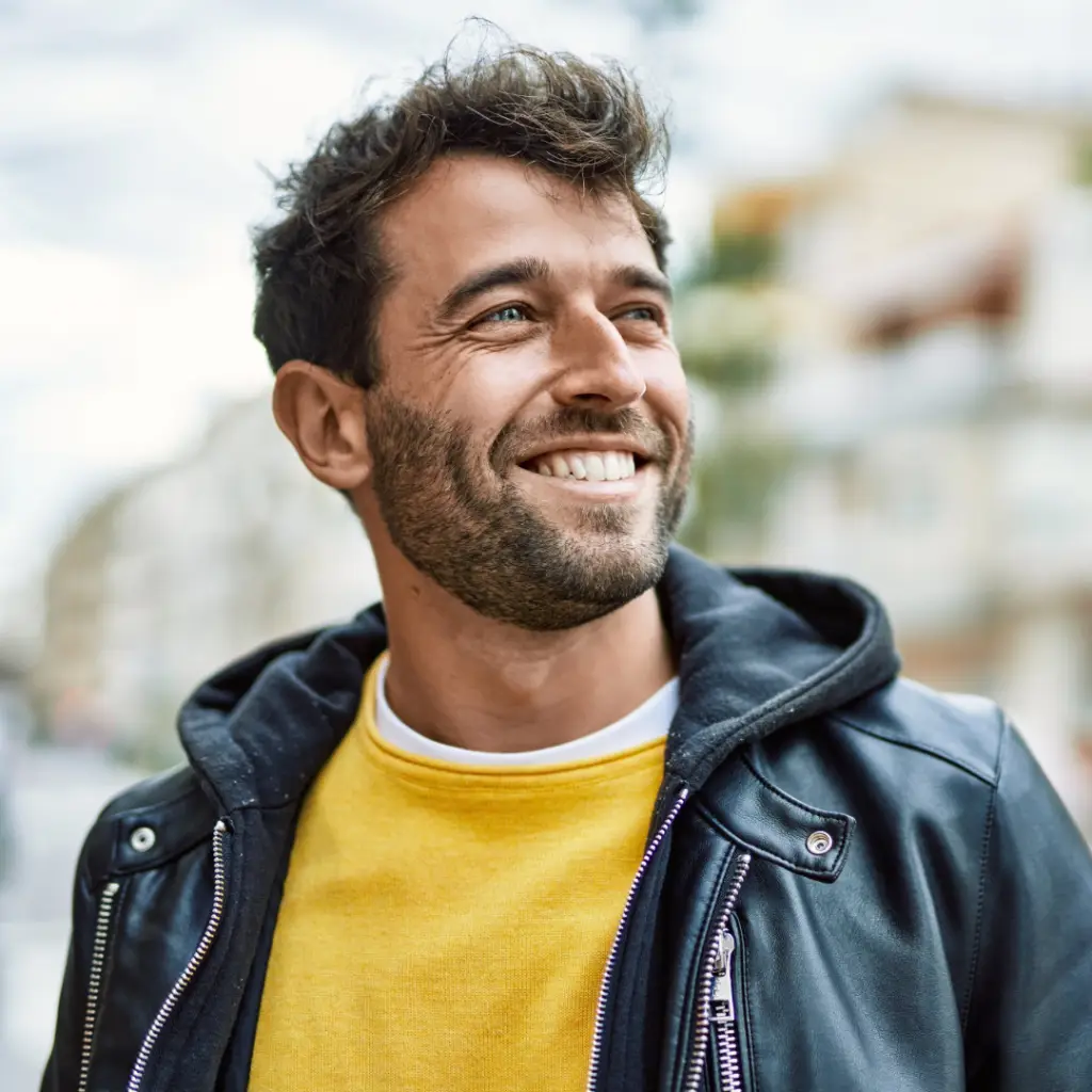 Man smiling wearing a leather jacket and looking into the distance