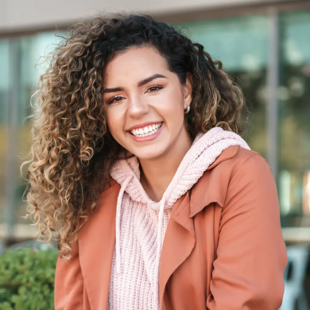Smiling girl withh curly hair and a pink jacket